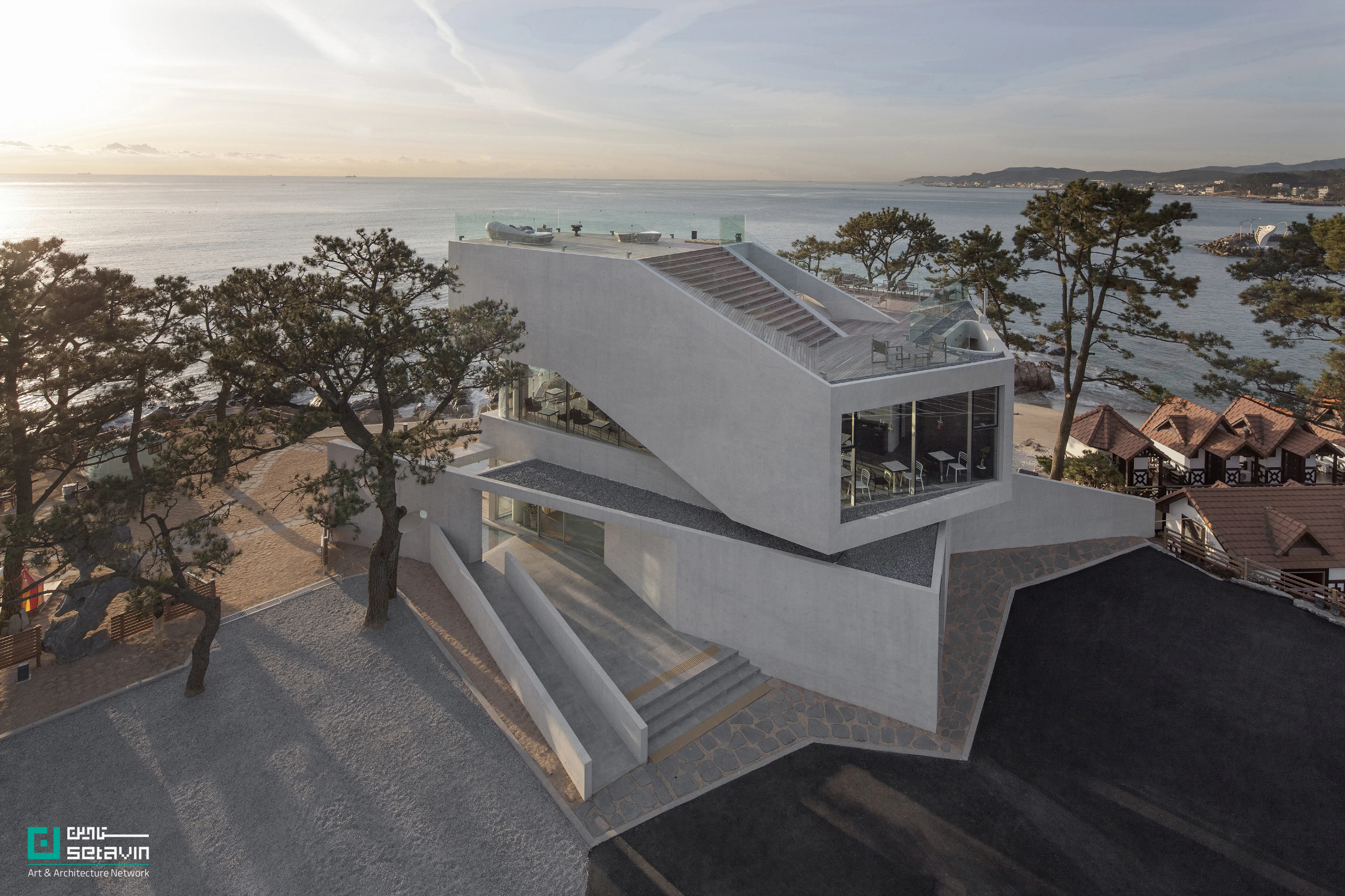کافه Gijang Waveon در نزدیکی بوسان کره‌جنوبی، اثر Heesoo Kwak + IDMM Architects؛ حجمی پله‌پله با راهروهای طولانی، void مرکزی و سکوهای سنتی زیر کاج، برای تماشای چندلایه دریا و ساحل.